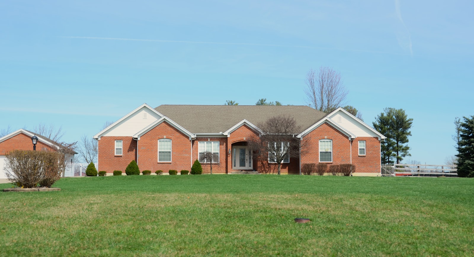 Brick home with manicured front lawn and shaped shrubs