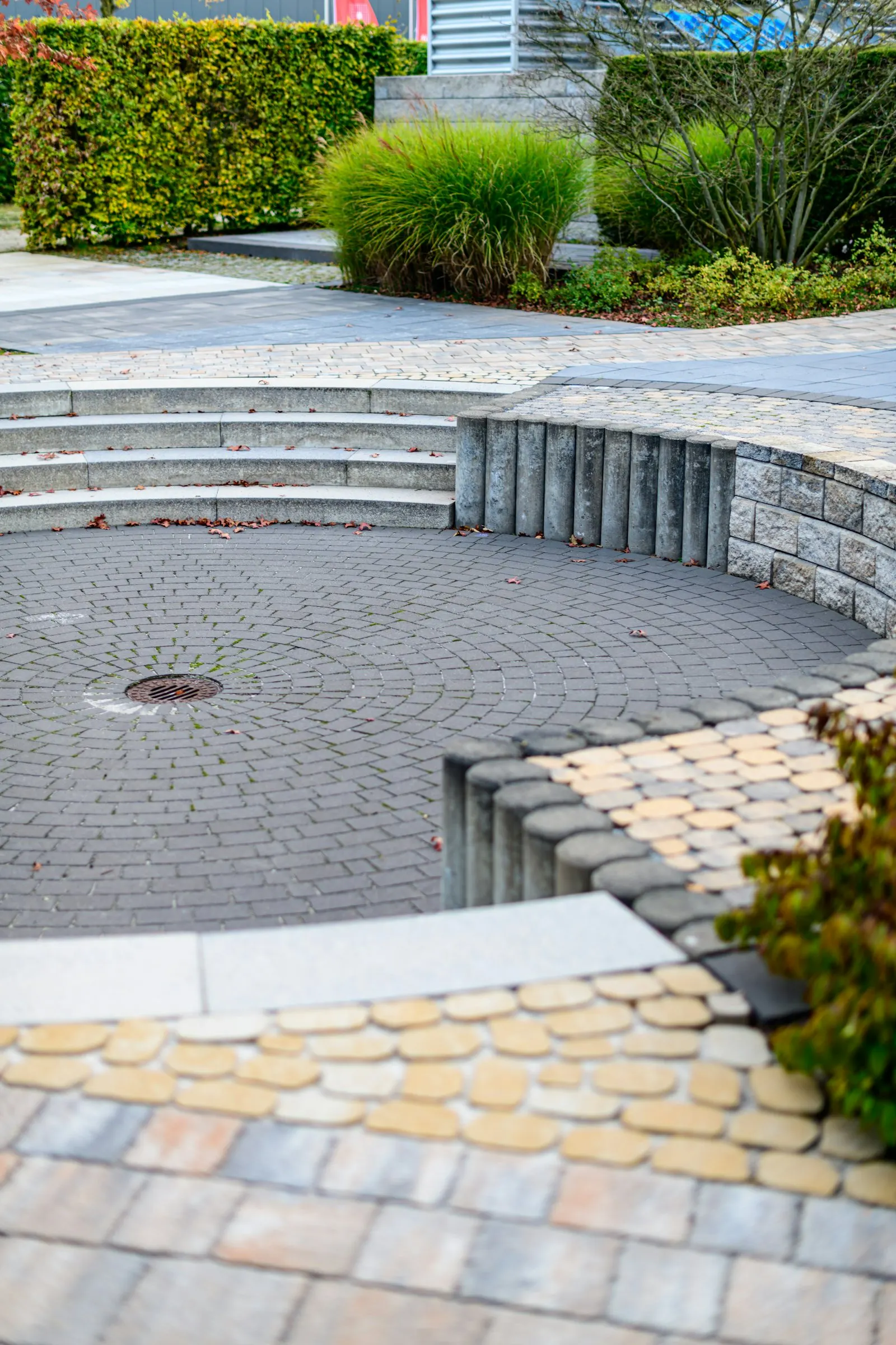 Curved paver patio with seating area and shrub border at a residential property