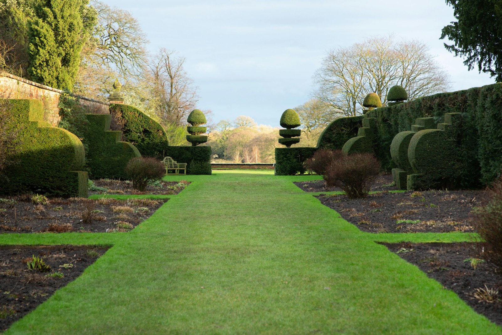Long green residential lawn with mature trees framing a side yard