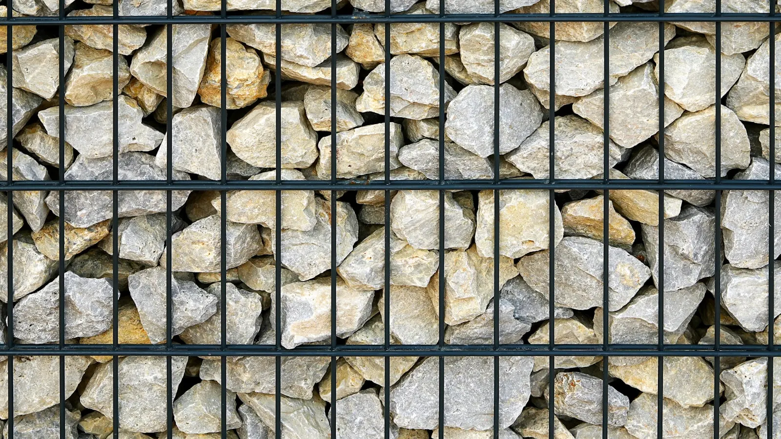 Tan dry-stack stone retaining wall along a residential property edge